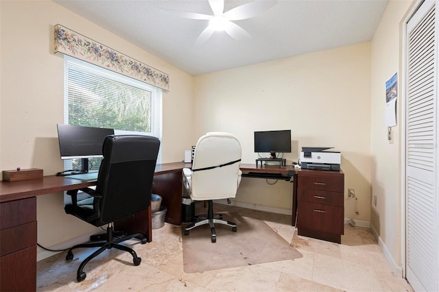 office space featuring a ceiling fan and baseboards