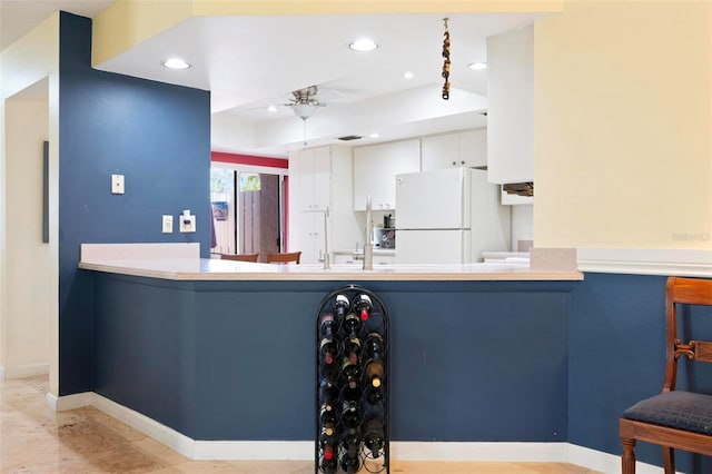 kitchen featuring a raised ceiling, a ceiling fan, freestanding refrigerator, recessed lighting, and baseboards