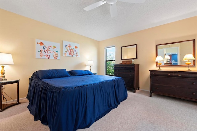 bedroom featuring baseboards, light colored carpet, a ceiling fan, and a textured ceiling