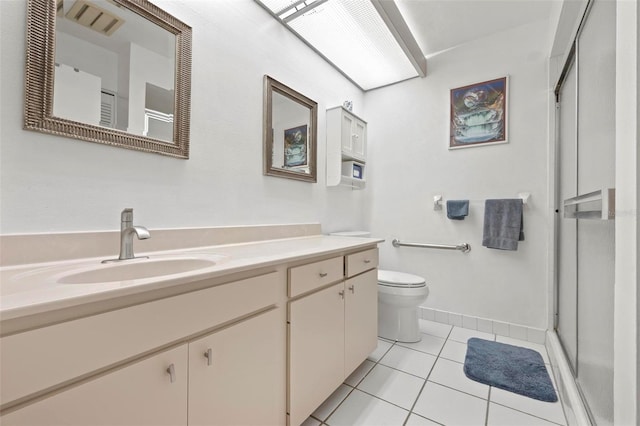 bathroom featuring toilet, a shower stall, tile patterned flooring, baseboards, and vanity