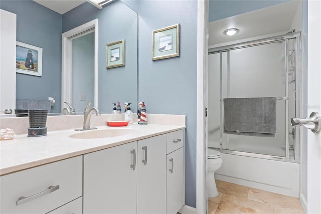 full bathroom with tile patterned floors, toilet, vanity, and bath / shower combo with glass door