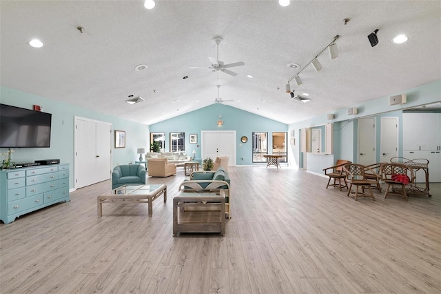 living area with ceiling fan, vaulted ceiling, light wood-style flooring, rail lighting, and a textured ceiling