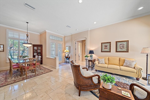 living room with crown molding, arched walkways, visible vents, and baseboards