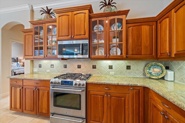 kitchen featuring decorative backsplash, crown molding, light stone counters, and stainless steel appliances