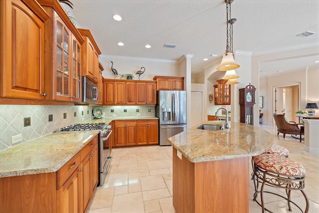 kitchen featuring brown cabinetry, visible vents, arched walkways, a sink, and appliances with stainless steel finishes