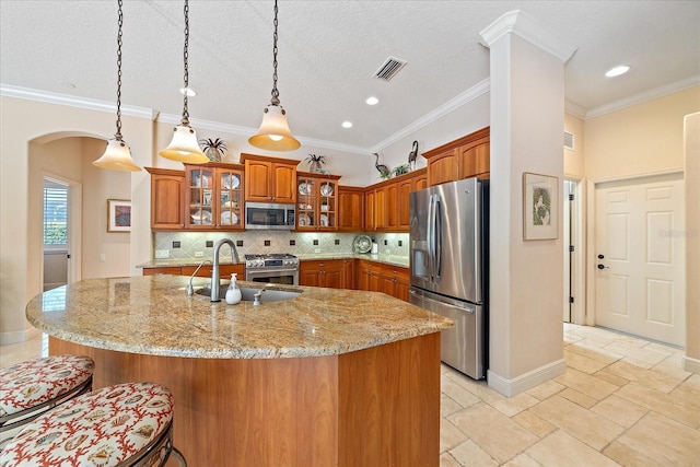 kitchen with visible vents, arched walkways, brown cabinetry, stainless steel appliances, and a sink