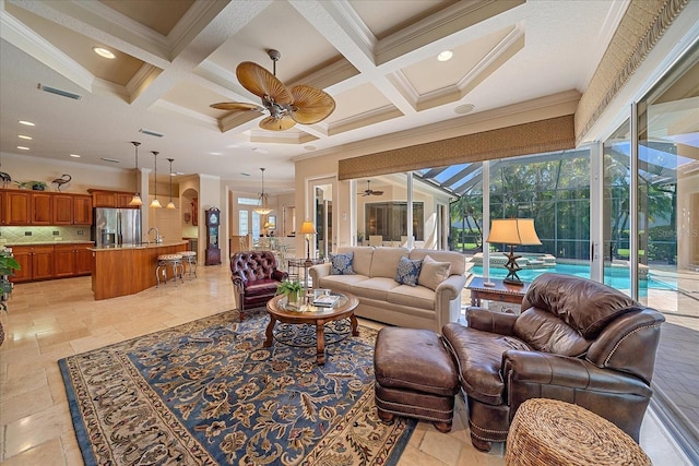 living room featuring ceiling fan, beamed ceiling, ornamental molding, stone tile floors, and coffered ceiling