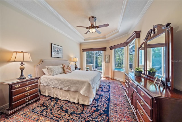 bedroom with access to exterior, baseboards, crown molding, and a tray ceiling