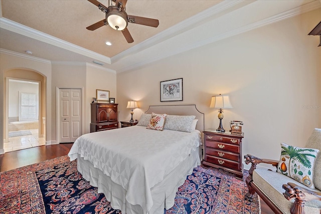 bedroom with visible vents, ornamental molding, arched walkways, a raised ceiling, and dark wood-style flooring