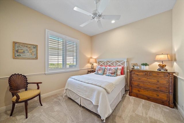 bedroom featuring light colored carpet, a ceiling fan, and baseboards