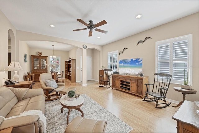 living room with recessed lighting, light wood-style floors, arched walkways, and plenty of natural light