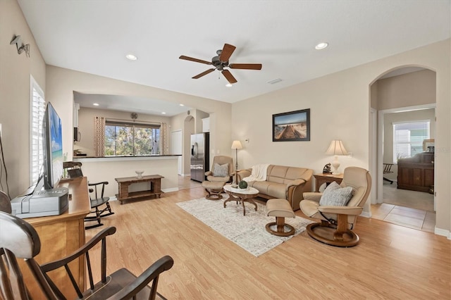 living room featuring plenty of natural light, light wood-style floors, and arched walkways