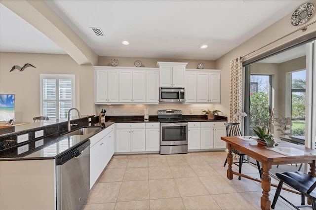 kitchen featuring visible vents, a sink, backsplash, appliances with stainless steel finishes, and light tile patterned floors