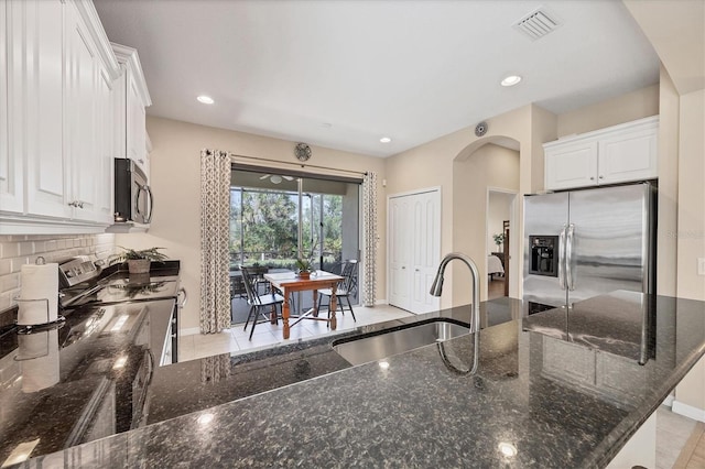 kitchen featuring a sink, backsplash, dark stone counters, appliances with stainless steel finishes, and white cabinets