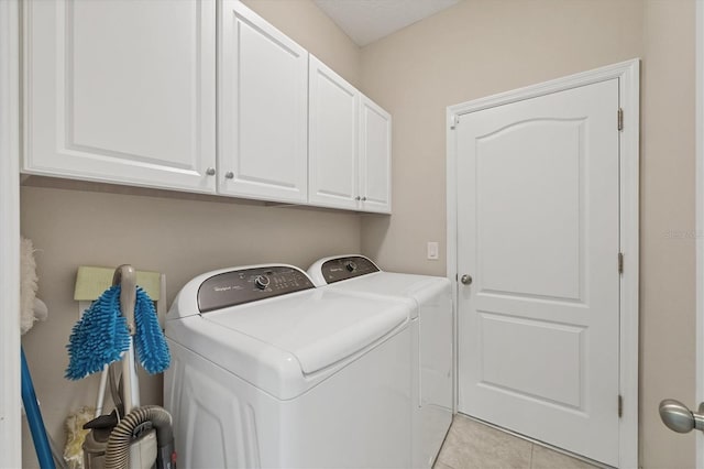 laundry room with cabinet space, light tile patterned flooring, and washer and clothes dryer