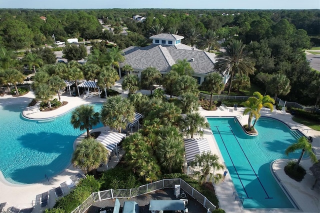 community pool featuring a patio, fence, and a view of trees