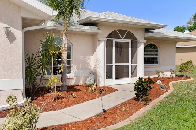 property entrance with stucco siding and a shingled roof