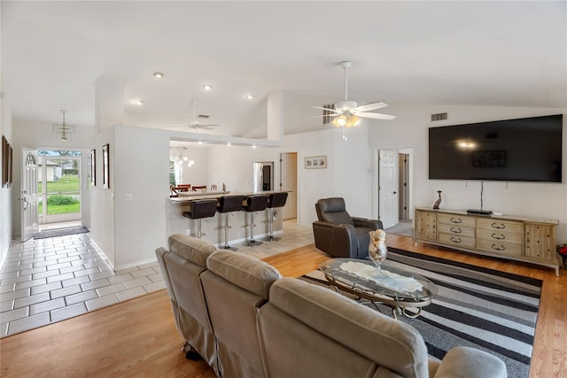 living room with lofted ceiling, light wood-style flooring, a ceiling fan, and visible vents