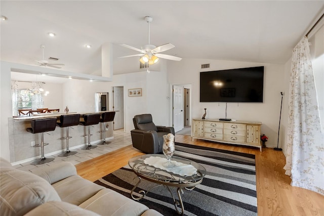 living room with lofted ceiling, light wood-style flooring, and ceiling fan with notable chandelier