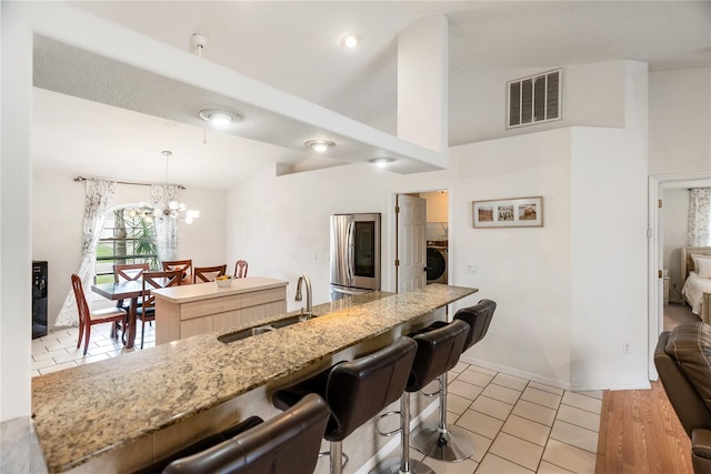 kitchen featuring visible vents, a kitchen island, a sink, smart refrigerator, and a kitchen bar