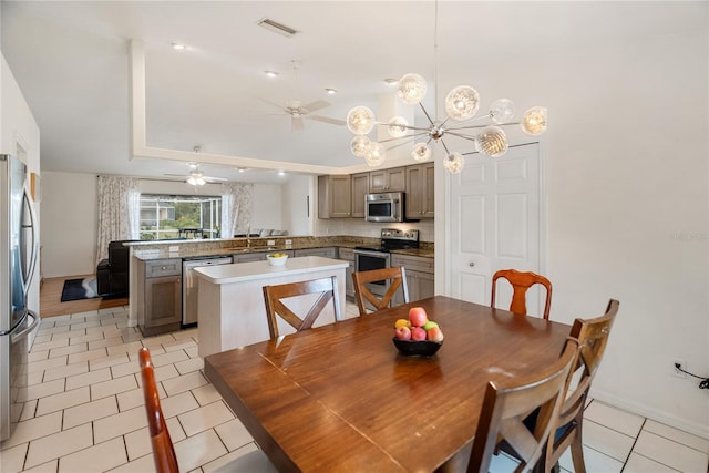 dining area with light tile patterned floors, baseboards, visible vents, ceiling fan, and a raised ceiling