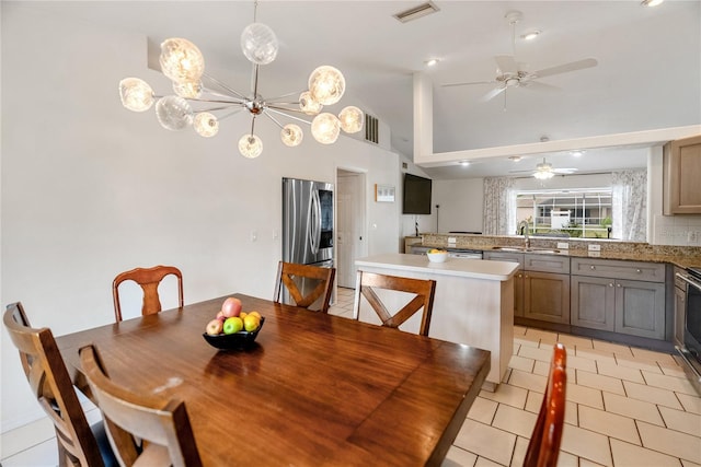 dining area featuring lofted ceiling, light tile patterned floors, ceiling fan with notable chandelier, and visible vents