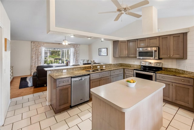 kitchen featuring a ceiling fan, a sink, open floor plan, appliances with stainless steel finishes, and a peninsula