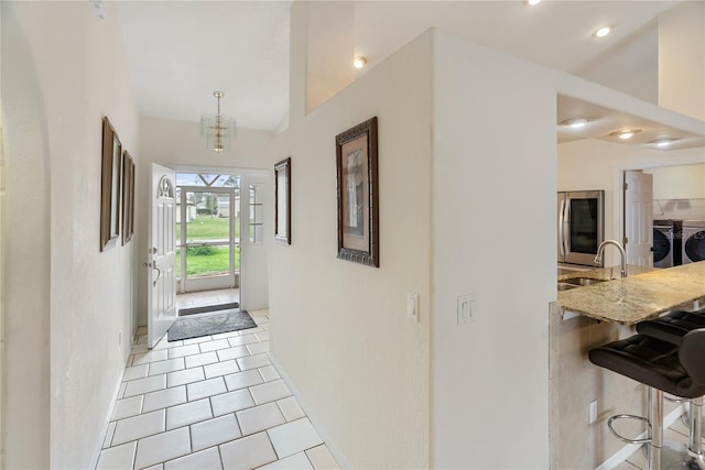 tiled entryway featuring a sink, a notable chandelier, recessed lighting, and washing machine and clothes dryer