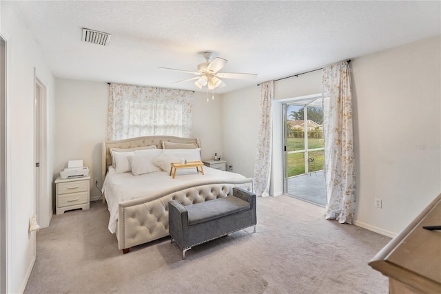 bedroom with a ceiling fan, visible vents, light carpet, a textured ceiling, and access to outside