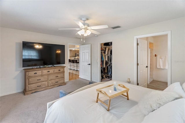 bedroom featuring visible vents, connected bathroom, baseboards, light colored carpet, and a closet