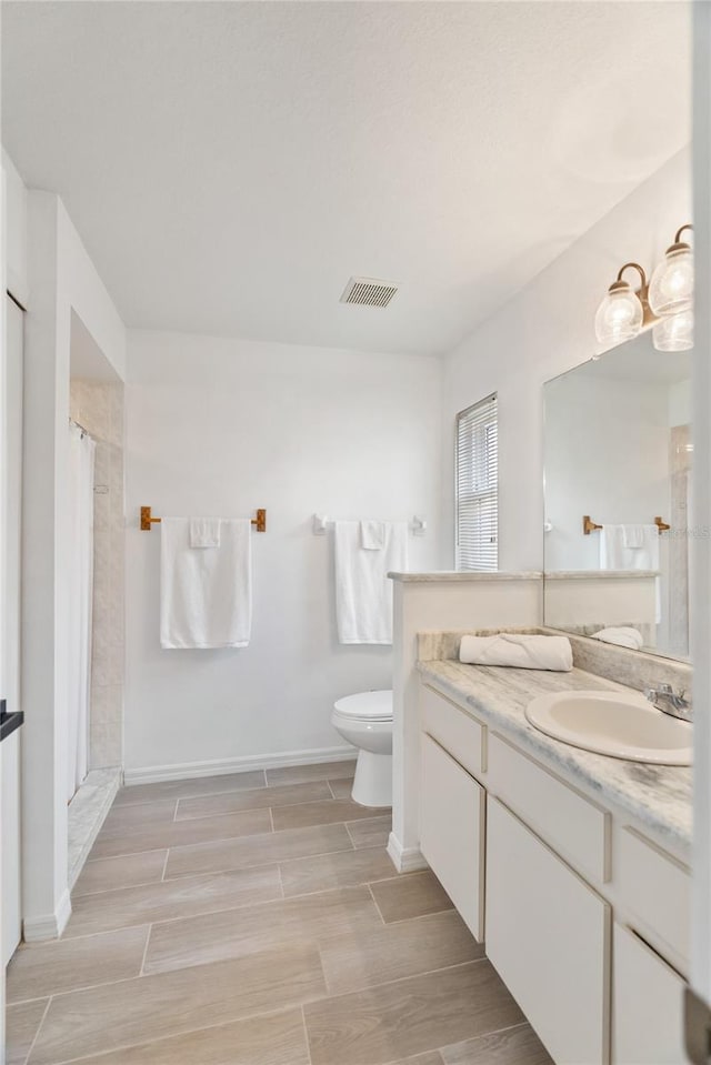 full bath with visible vents, wood tiled floor, toilet, a shower with curtain, and vanity