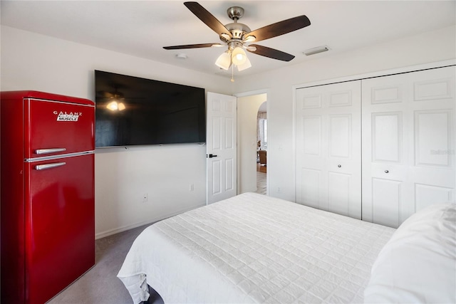 carpeted bedroom featuring a ceiling fan, arched walkways, visible vents, and a closet