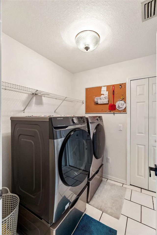 clothes washing area with a textured ceiling, laundry area, visible vents, and washer and clothes dryer