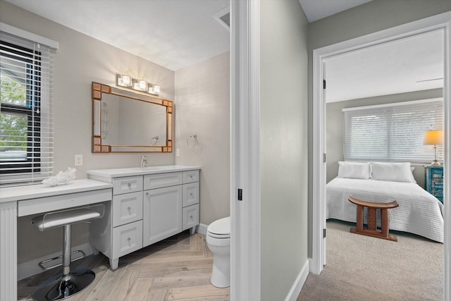 bathroom with vanity, ensuite bath, toilet, and baseboards