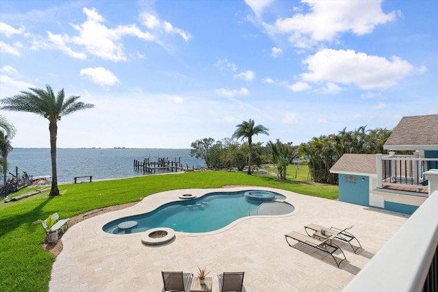 view of swimming pool featuring a patio, a yard, a water view, and a pool with connected hot tub