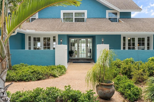 property entrance with french doors, a shingled roof, and stucco siding