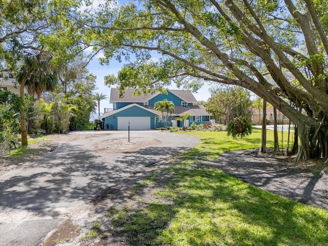 view of front of house featuring aphalt driveway, a garage, and a front lawn