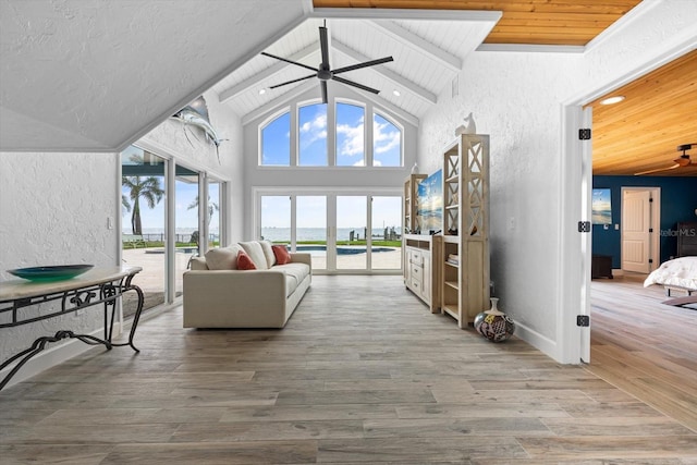 living area with a ceiling fan, wood finished floors, high vaulted ceiling, wood ceiling, and a textured wall