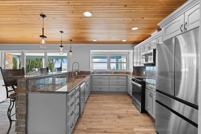 kitchen with a sink, appliances with stainless steel finishes, wooden ceiling, a kitchen breakfast bar, and light wood-type flooring