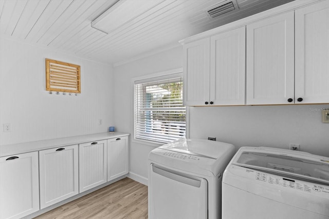 washroom featuring washing machine and dryer, cabinet space, light wood-style floors, and visible vents