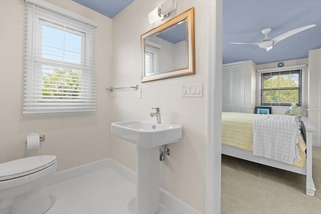 bathroom with baseboards, ensuite bath, ceiling fan, tile patterned flooring, and toilet