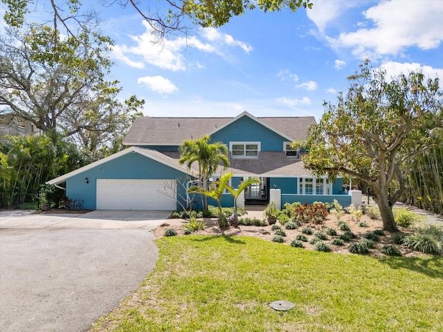 view of front facade featuring stucco siding, a front yard, an attached garage, and driveway