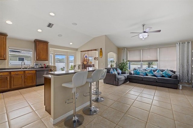 kitchen featuring visible vents, open floor plan, a kitchen breakfast bar, arched walkways, and stainless steel dishwasher