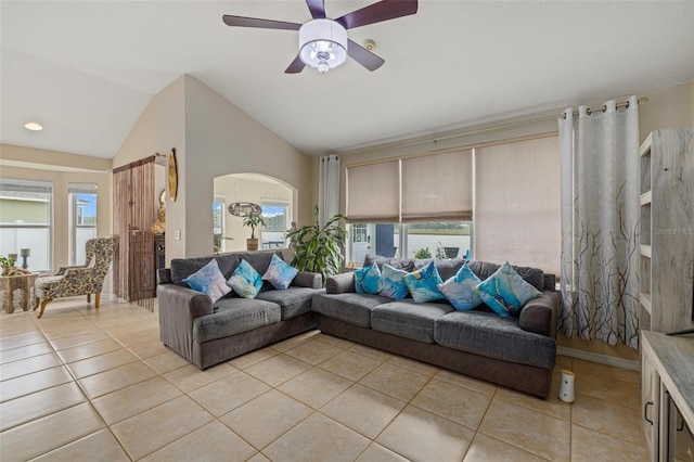 living area featuring vaulted ceiling, light tile patterned flooring, a ceiling fan, and arched walkways