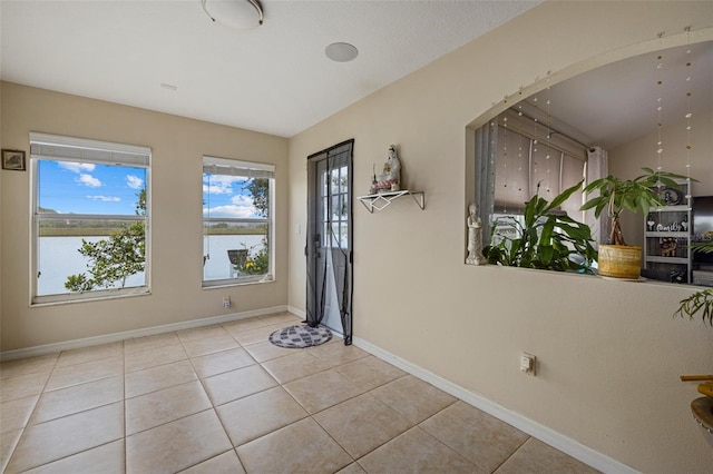 tiled foyer with baseboards and a water view