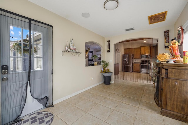 entrance foyer featuring light tile patterned flooring, visible vents, arched walkways, and baseboards