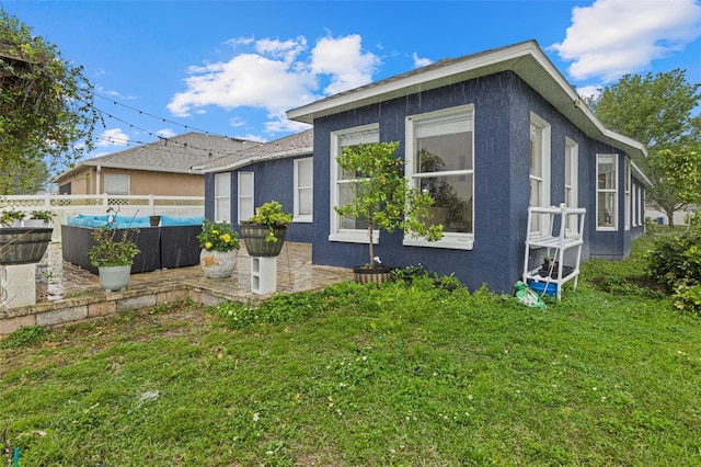 view of property exterior featuring a yard, fence, and stucco siding