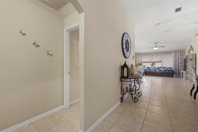 hallway featuring light tile patterned flooring, baseboards, visible vents, and arched walkways