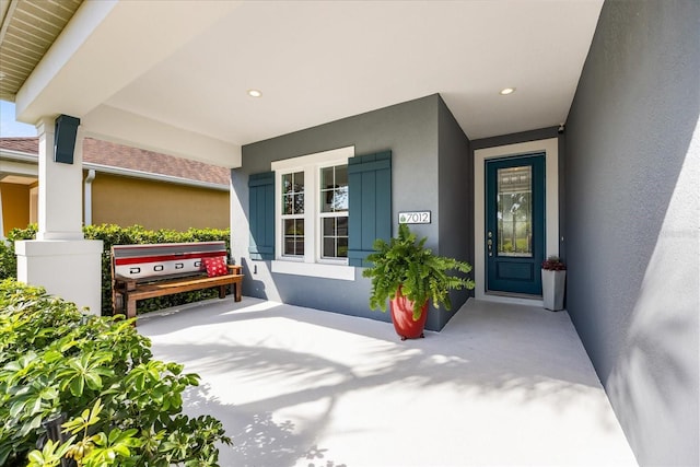 view of exterior entry with a porch and stucco siding