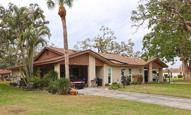 view of front facade featuring solar panels, concrete driveway, a front yard, and stucco siding